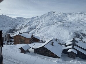 A snow-covered mountain village with traditional wooden houses and a ski resort in the background. - At the foot of the ski slopes, sleeps 4–5. Elevation: 2,000 m. Exceptional view.   (Les Belleville)