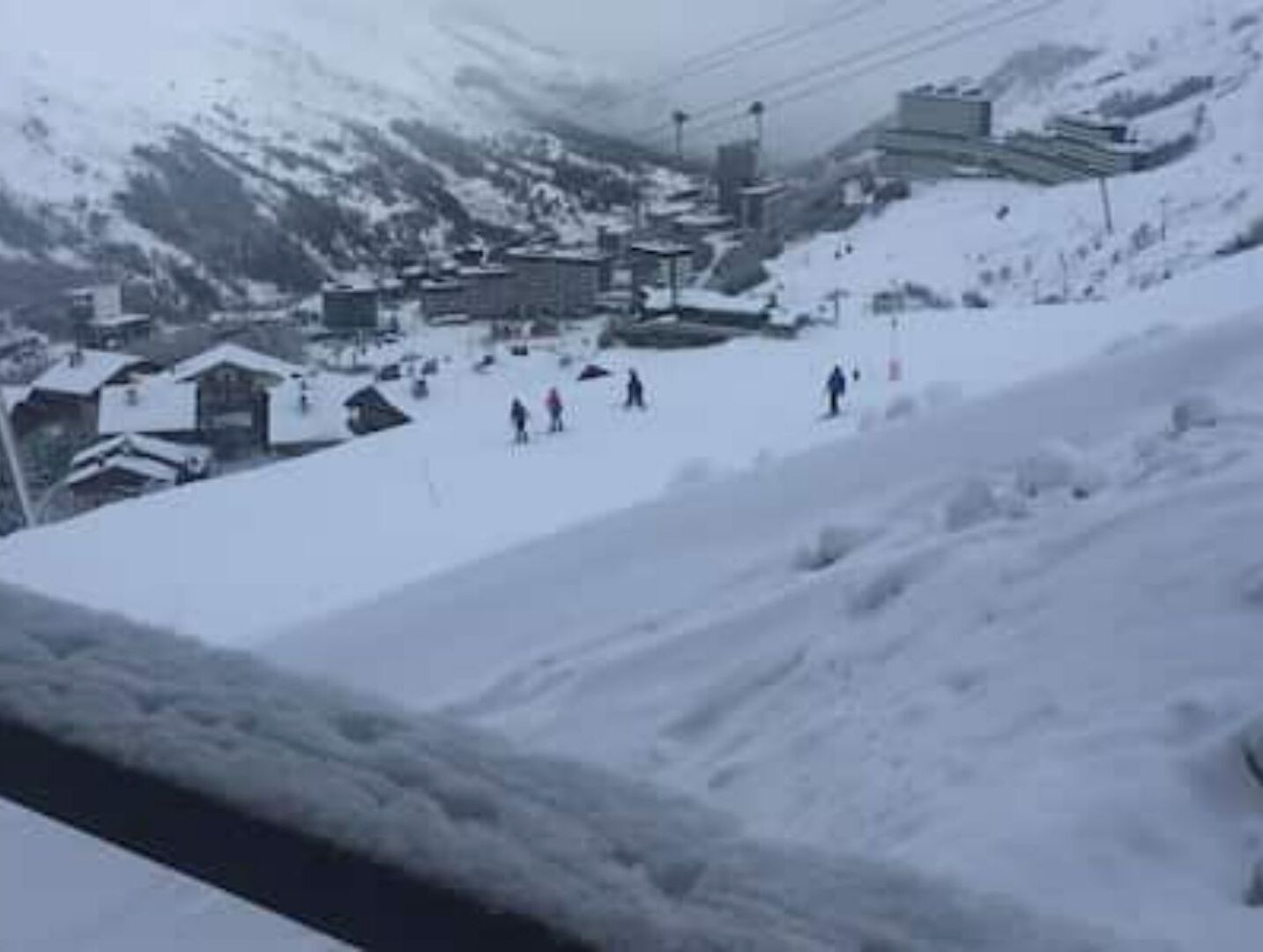 A snow-covered mountain area with buildings and a ski slope.