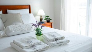 A neatly made bed with white linens, a lavender plant, and folded towels. - Solar House Babina 1 (Korcula)