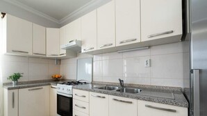A modern kitchen with white cabinets, a granite countertop, stainless steel appliances, and a gas stove. - Solar House Babina 1 (Korcula)