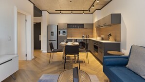 A modern kitchen with a dining area, a sofa, and a washing machine.