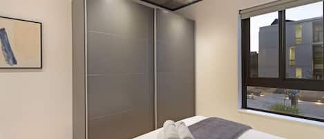 Un dormitorio moderno con una cama grande, cortinas grises y una ventana con vistas a la ciudad.