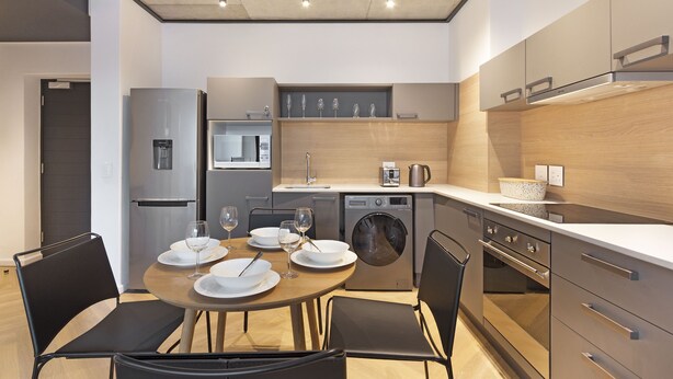 A modern kitchen with a dining area, stainless steel appliances, and a built-in oven.