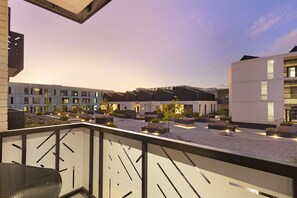 A modern building with a courtyard, featuring a mix of residential and commercial spaces, and a balcony with a metal chair. - Bridgewater View 415 by HostAgents  (Cape Town)