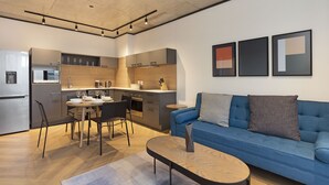 A modern kitchen with a dining area, a blue sofa, and artwork on the wall.