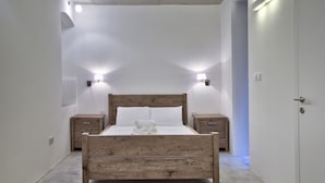 A bedroom with a wooden bed, two bedside tables, and wall-mounted lights. - Vallettastay - Casa Zoe  (Valletta)