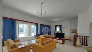 Ein großzügiges Wohnzimmer mit einer Sofagarnitur, einem Couchtisch und einem Fernseher.