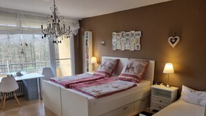 A bedroom with a large bed, bedside tables, a desk, and a chandelier.
