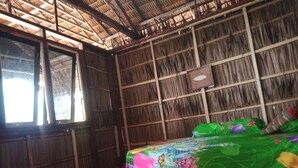 A room with a bed covered in a colorful blanket, wooden walls, and a thatched roof. - marine homestay (Pulau Fam)