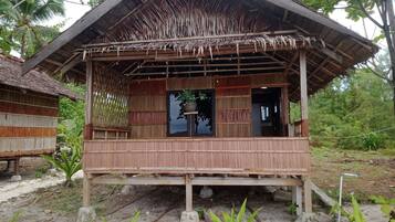 A wooden structure with a thatched roof, a window, and a door.