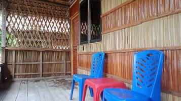 A covered outdoor seating area with wooden walls and a lattice ceiling.