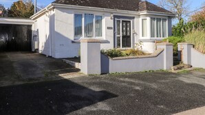 Una casa a un piano con tetto in tegole scure, pareti esterne bianche e un garage.