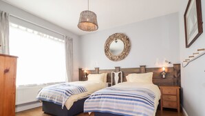 Una camera da letto con due letti, una testiera in legno, uno specchio e un comodino con una lampada.