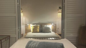 A neatly made bed with a rolled towel, a wooden headboard, and two wall-mounted lamps. - Dream villa KEUR BONHEUR in Saly: 3 suites, private pool, 100m from the beach (Saly)