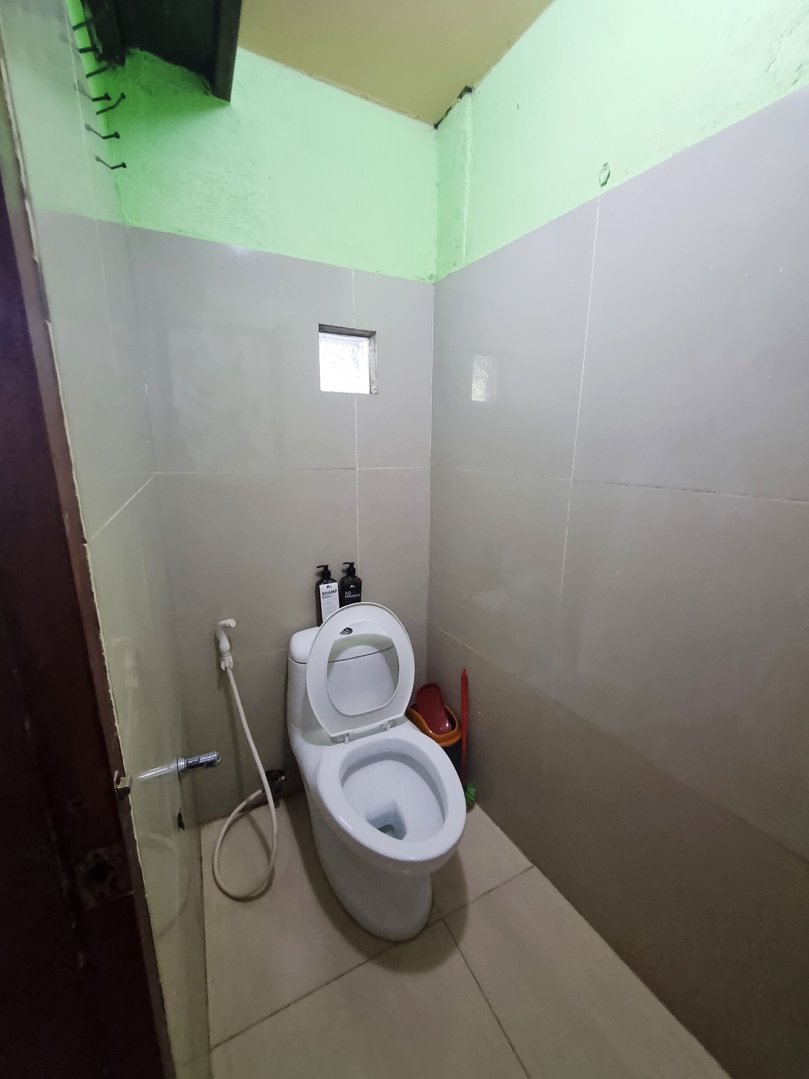 Un baño pequeño y sencillo con inodoro, ventana y ducha.