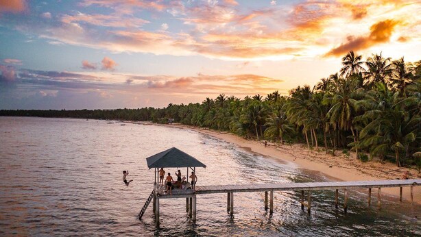 A beach with a wooden pier and a covered area. - Flo Island Home (General Luna)
