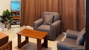 A living room with a sofa, armchair, and a wooden coffee table. - Flo Island Home (General Luna)