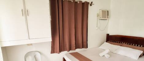 Quarto com cama, uma cadeira, guarda-roupa e cortina.