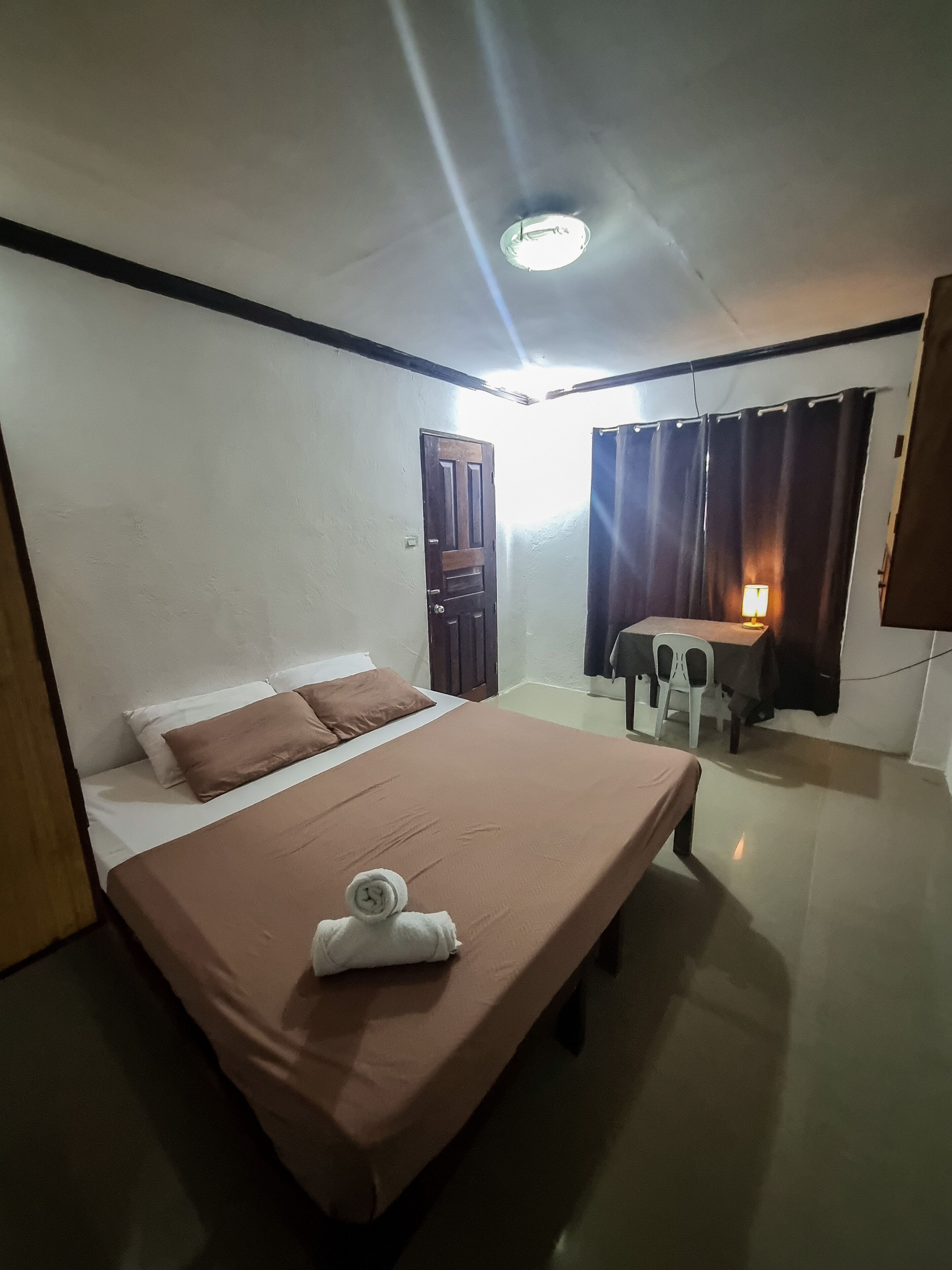 Una habitación de hotel con cama, escritorio, silla, lámpara y puerta.