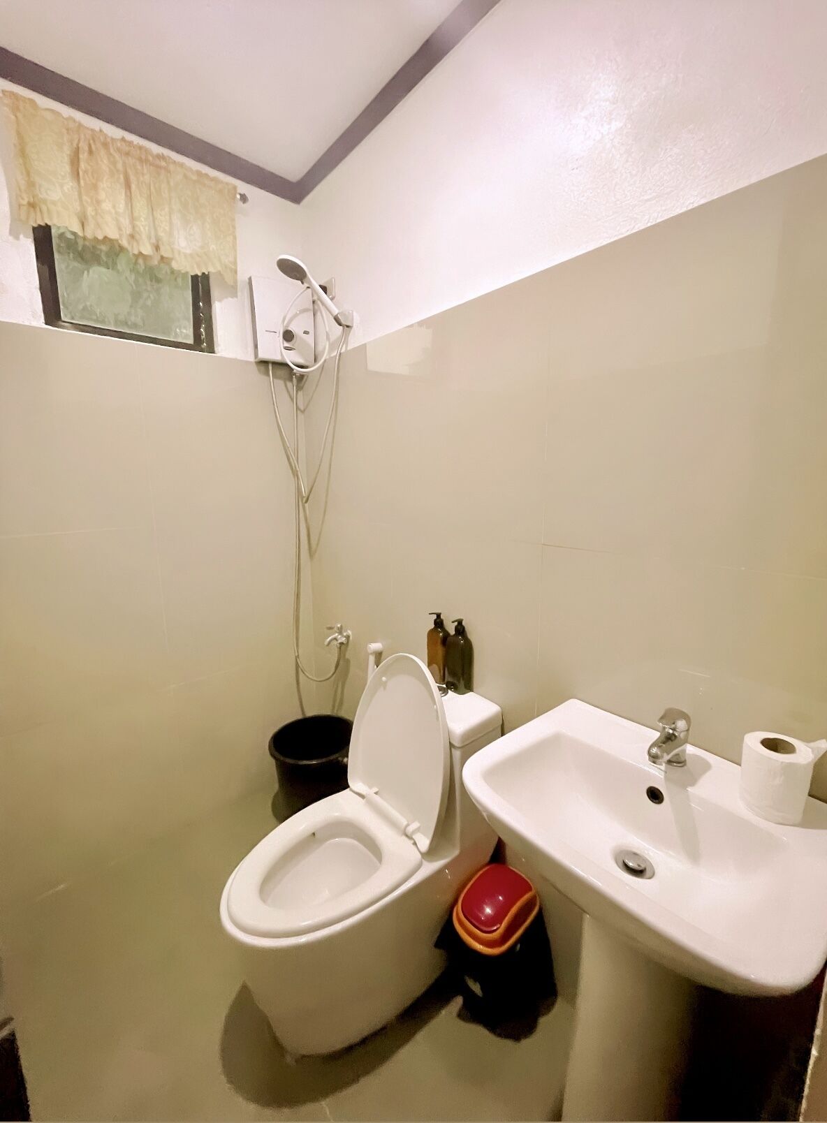 A bathroom with a toilet, bidet, sink, and a shower head mounted on the wall.