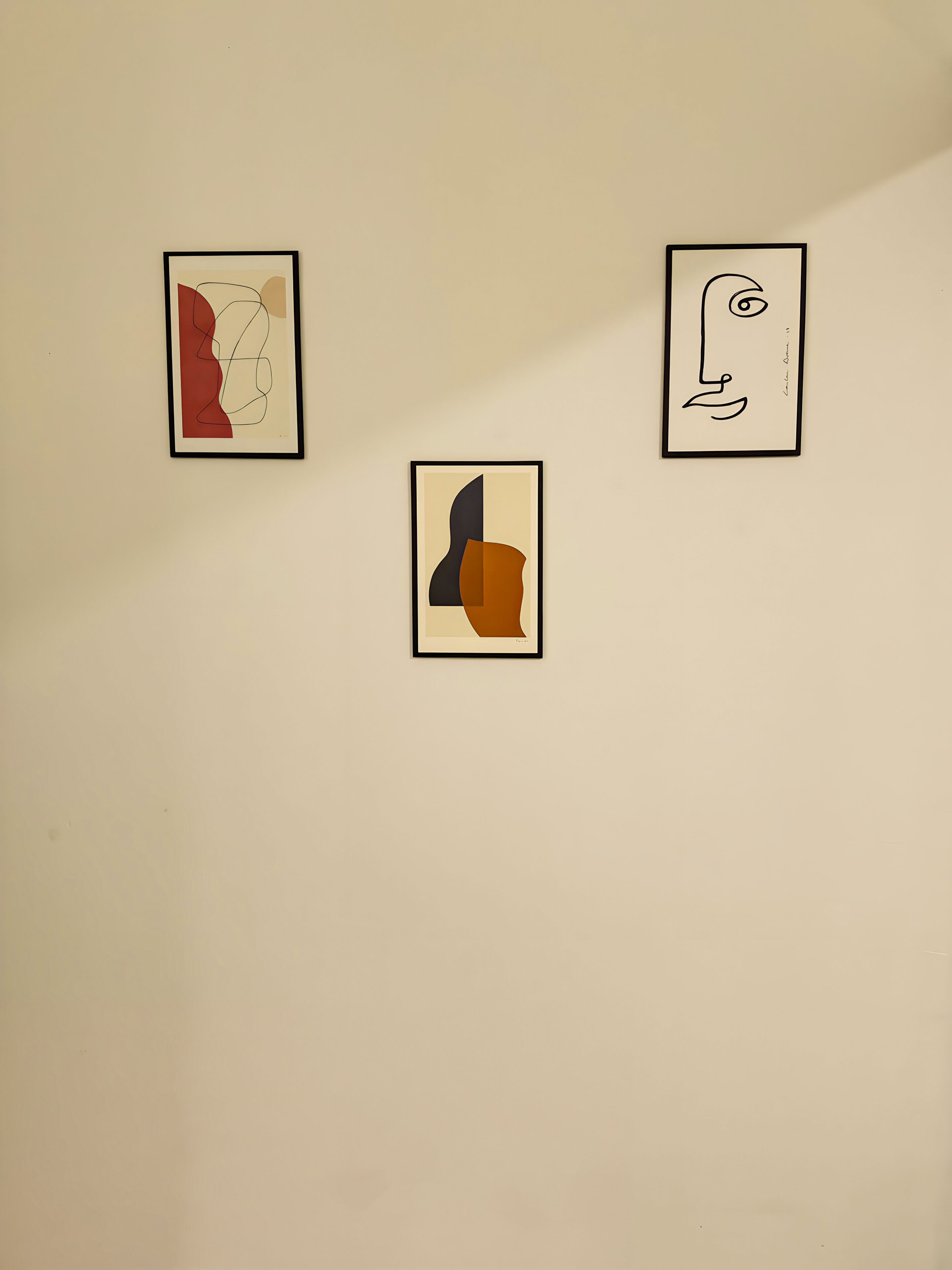 Three framed abstract artworks on a plain wall.