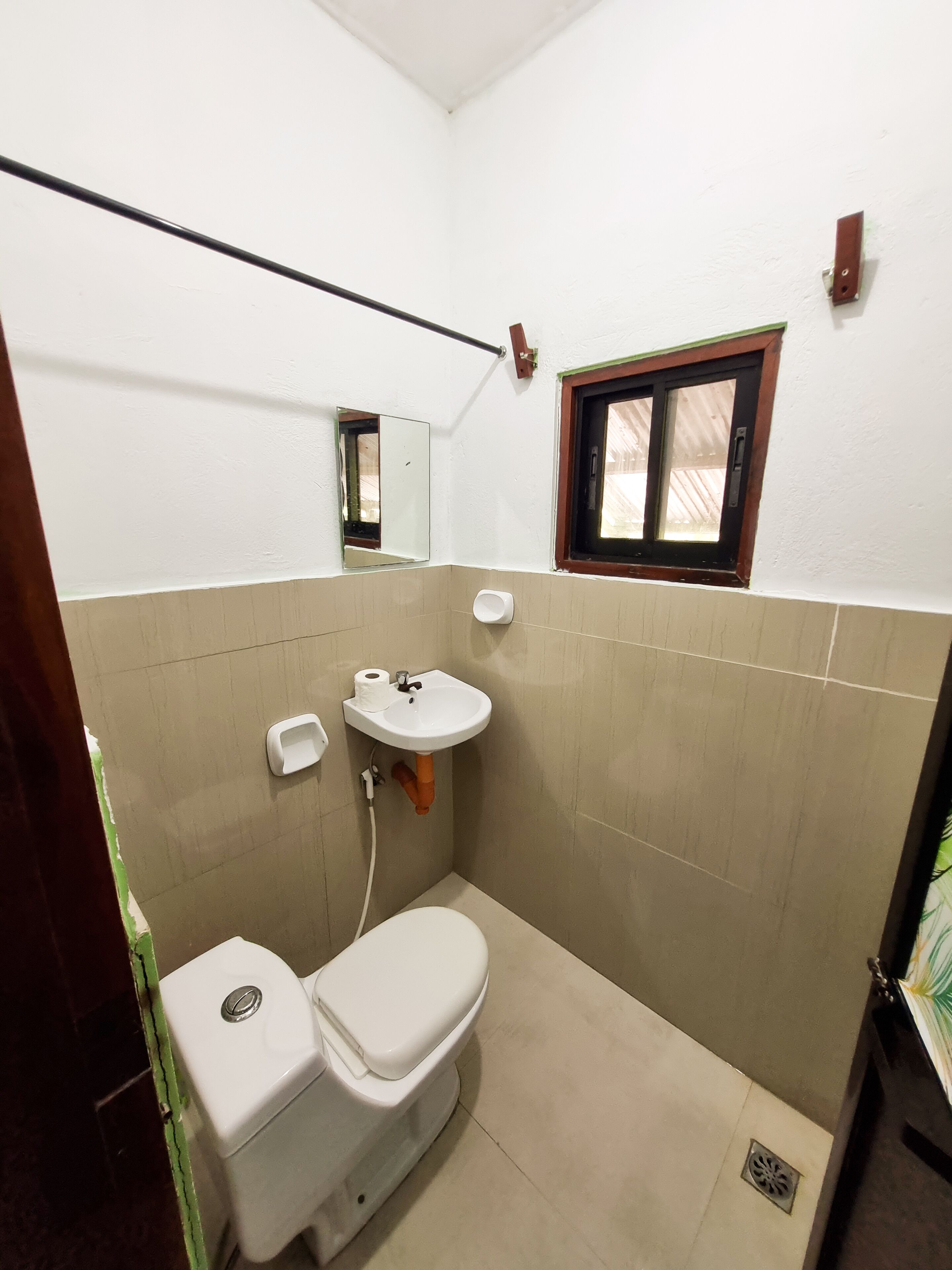 Baño pequeño y funcional con inodoro, lavamanos y espejo.