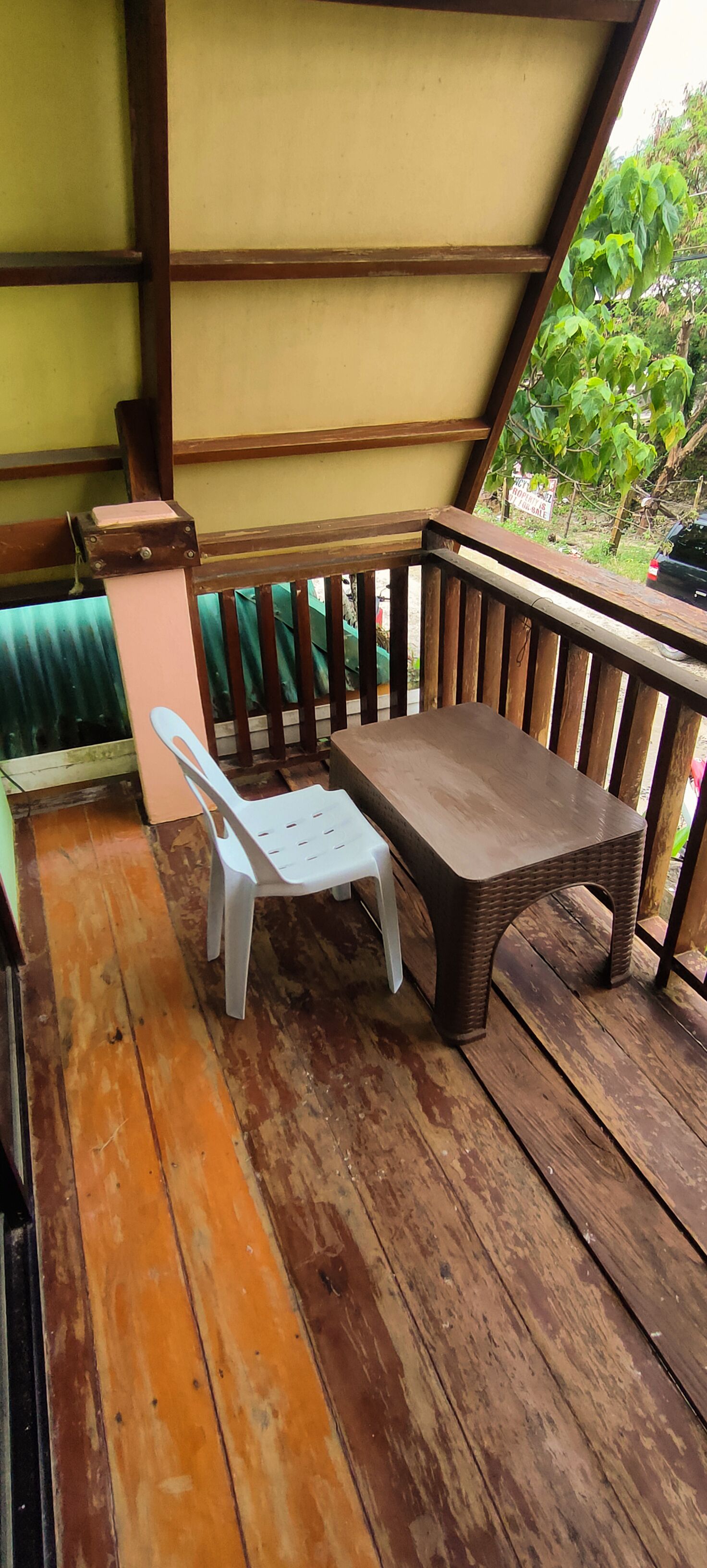 A wooden deck with a table and a white plastic chair.