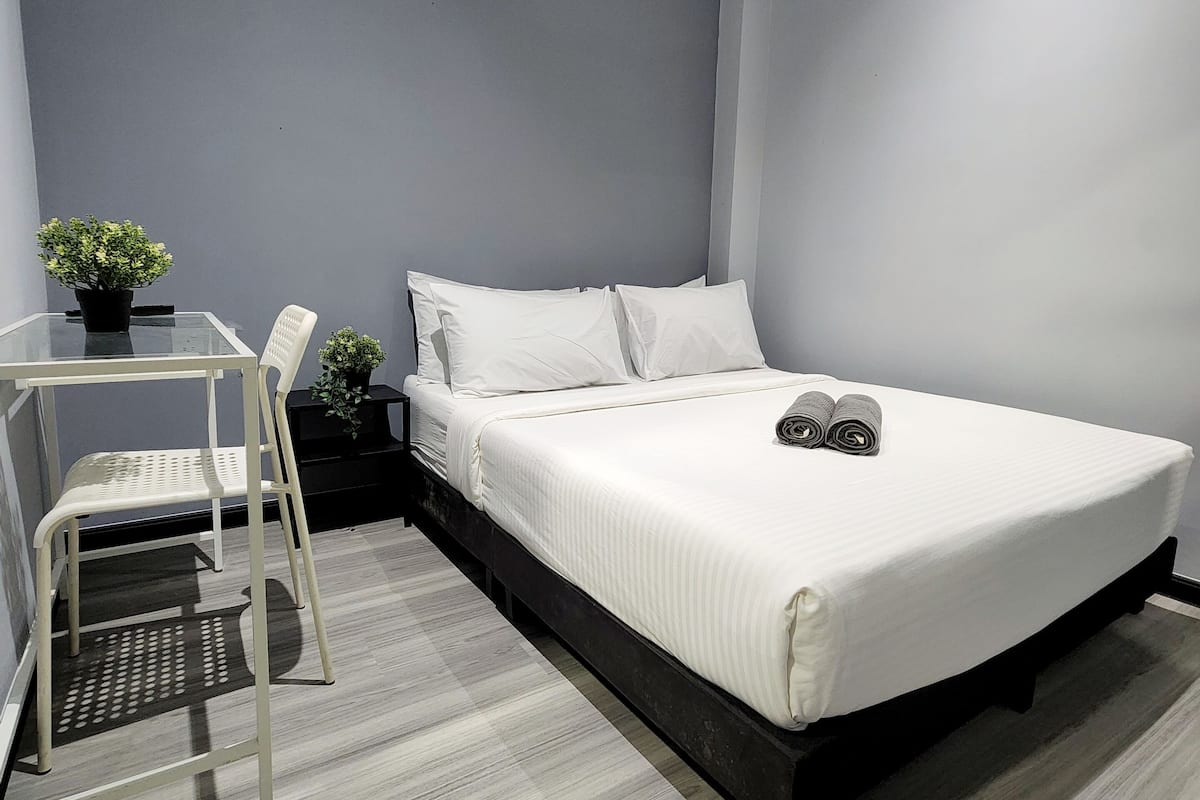 A modern bedroom with a bed, a small table, and a chair.
