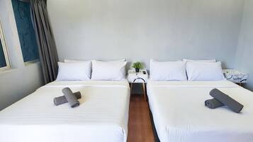 A hotel room with two beds, a window with curtains, a small table with a plant, and a nightstand with a phone.