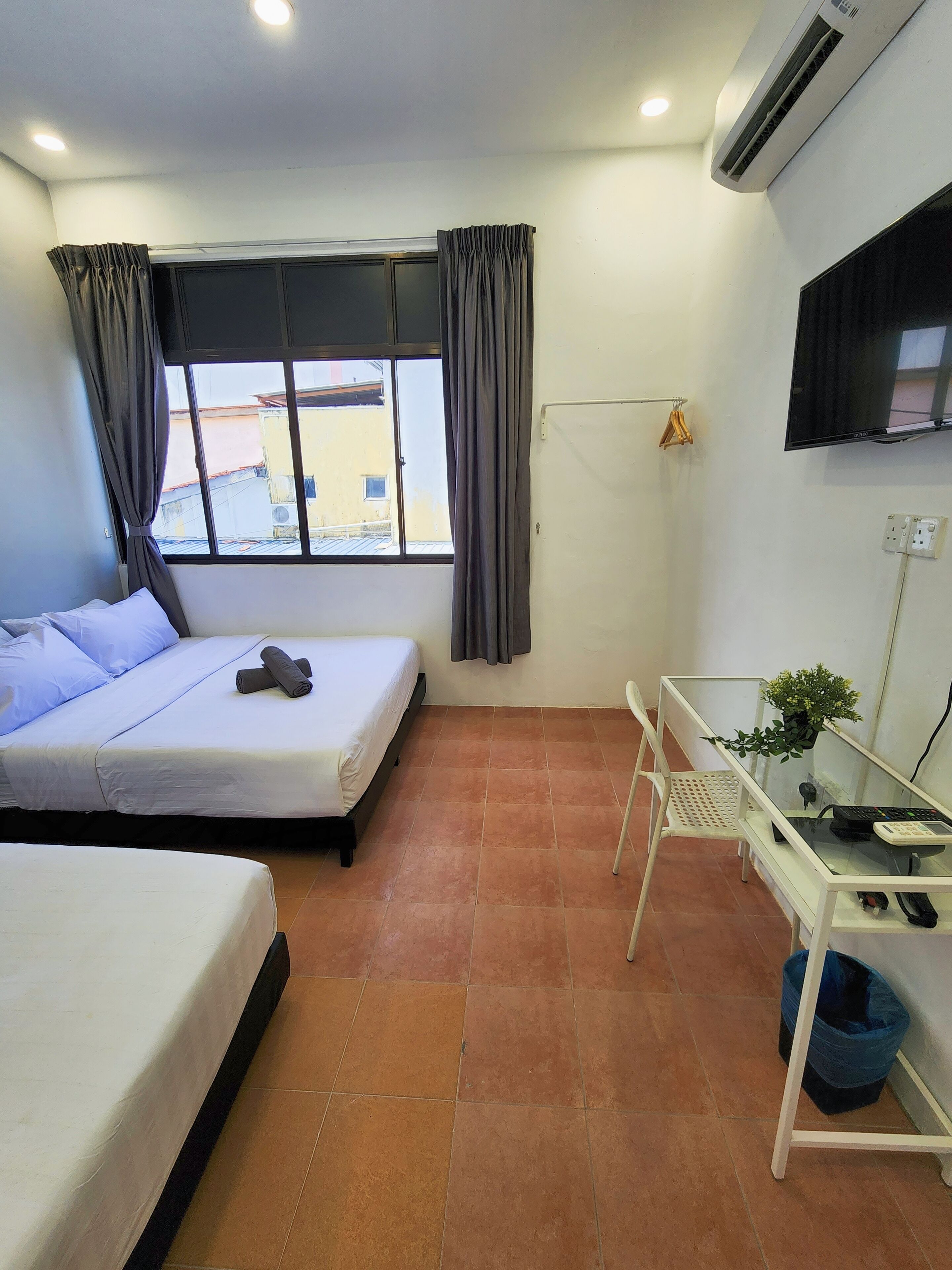 Une chambre d’hôtel avec deux lits, un bureau, une chaise, un climatiseur et une télévision.