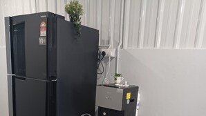 Un espacio de cocina compacto con un refrigerador negro, una cafetera pequeña y un mueble blanco con una toalla azul.