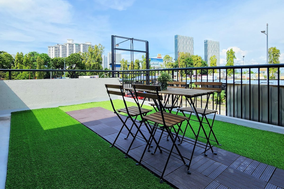 An outdoor seating area with a table and chairs, artificial grass, and a 7-Eleven sign in the background.