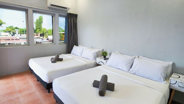 Habitación de hotel con dos camas, ventana con cortinas, aire acondicionado y vista al exterior.