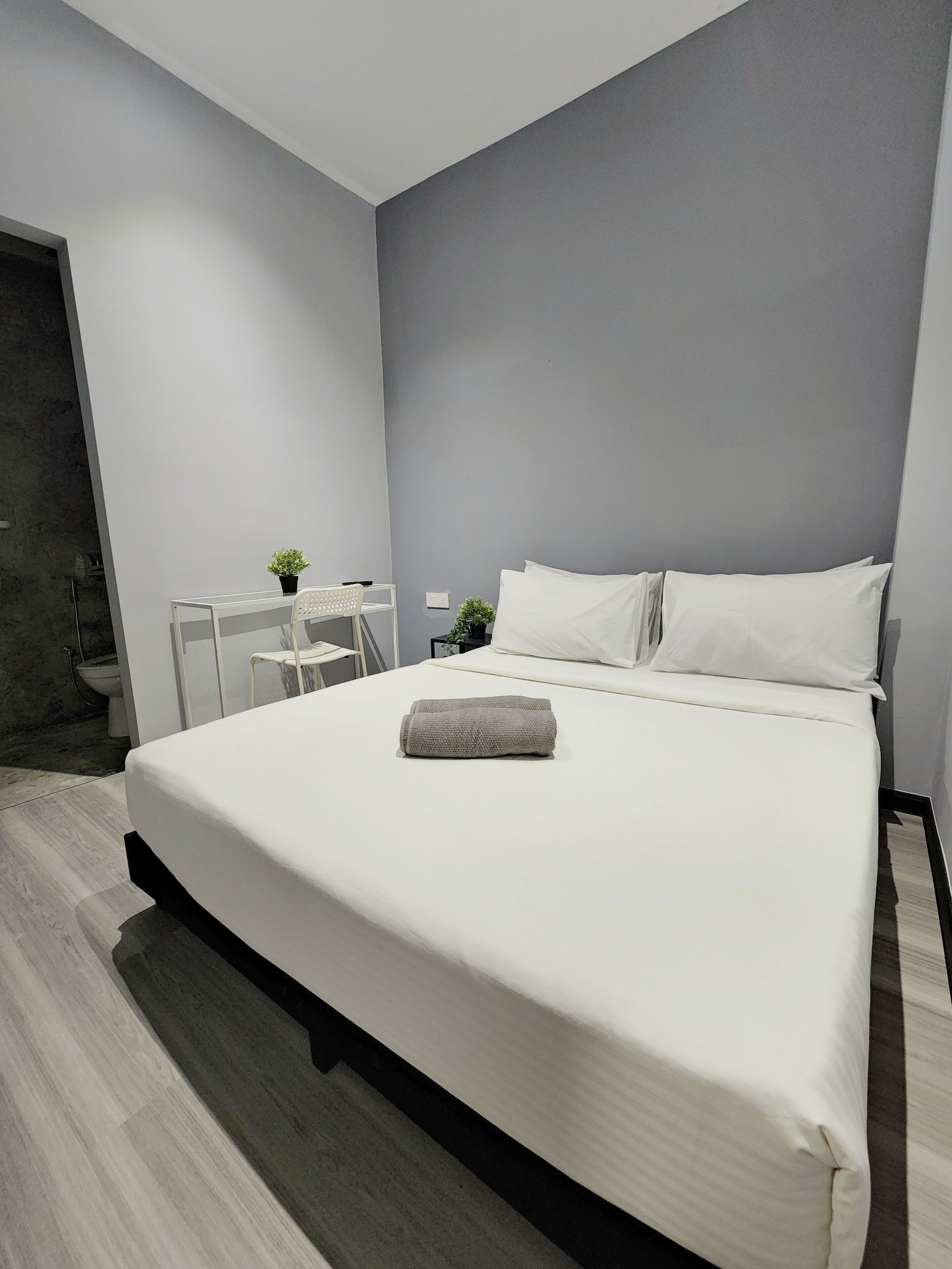 Een moderne hotelkamer met een groot bed, een klein bureau en een kamerplant.