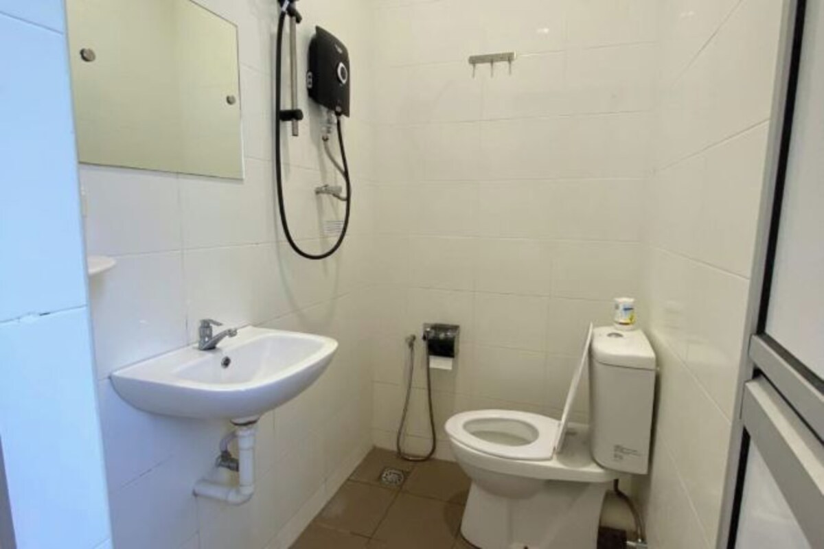 Un baño pequeño y limpio con lavamanos, inodoro y ducha de mano blancos.