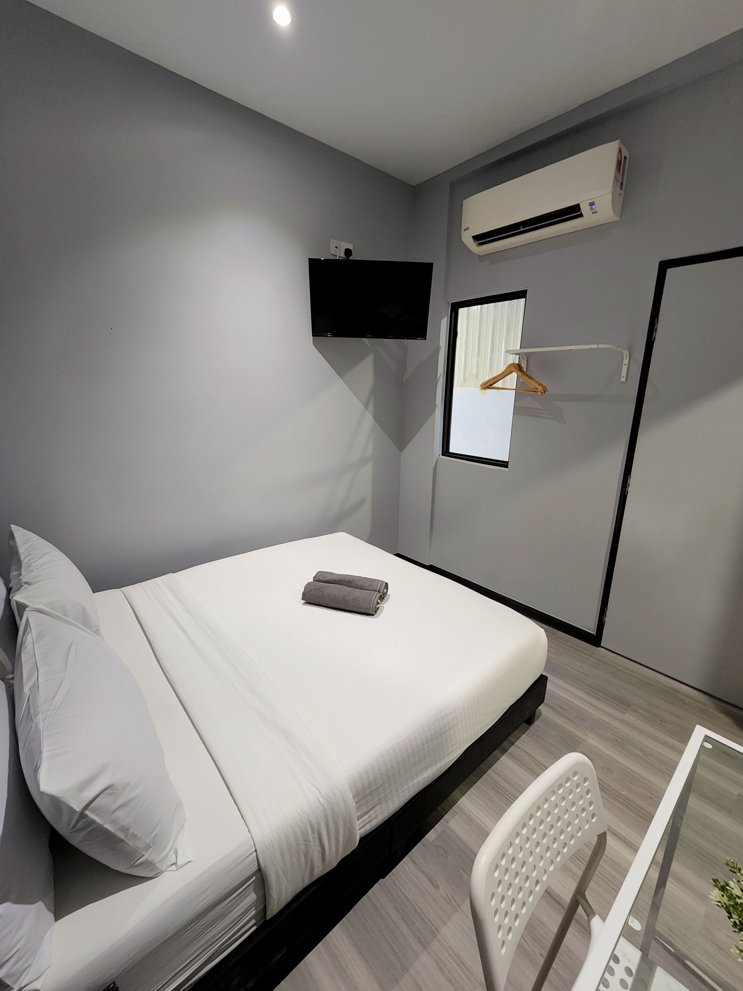 A modern bedroom with a bed, a TV, an air conditioner, and a window with a curtain.