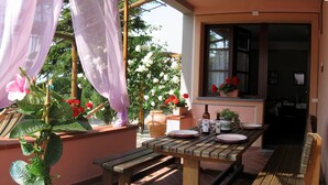 A wooden table set for dining with a window view, a potted plant, and a bottle of wine on the table.