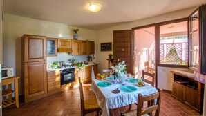 A kitchen with wooden cabinets, a dining table set with blue plates, and a view of a balcony with a lattice fence.