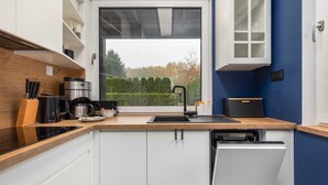 Una cocina moderna con gabinetes blancos, encimera negra y vistas al exterior.