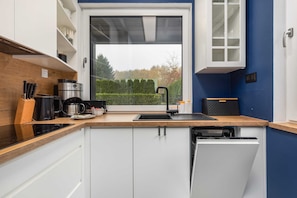 A modern kitchen with white cabinets, a black countertop, and a view of the outdoors.