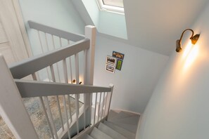 A staircase with white railings leading to a landing with a skylight.