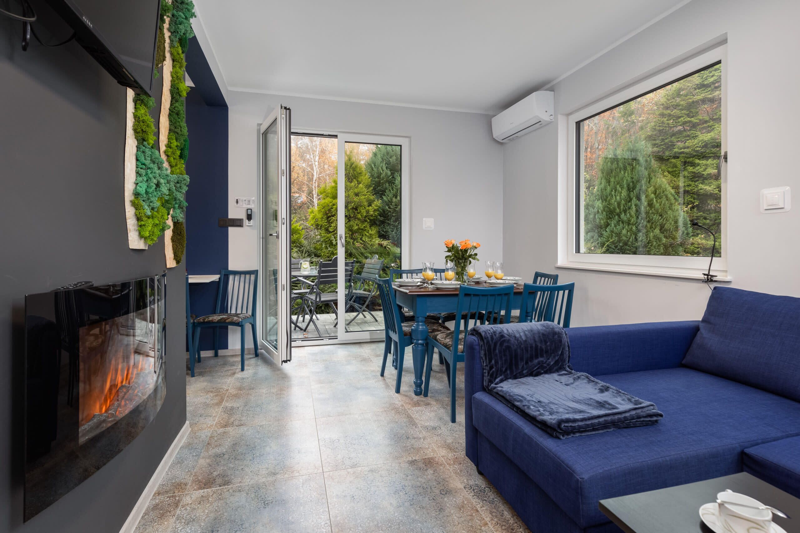 A modern living room with a blue sofa, a flat-screen TV, and a fireplace.