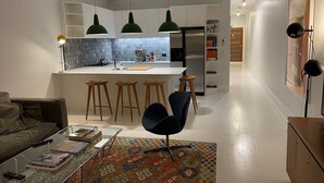 Una cocina moderna con una isla central, taburetes de bar e iluminación colgante.