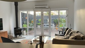 Una cocina moderna con un lavamanos central, una zona de comedor con mesa y sillas, y una sala de estar con sofá.