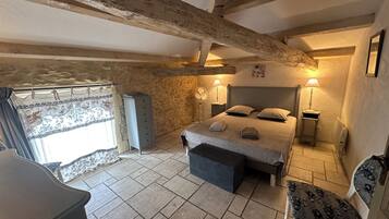 Une chambre à coucher avec un lit, des lampes de chevet, une commode, une chaise et une fenêtre avec des rideaux.