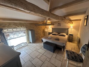 A bedroom with a bed, bedside lamps, a dresser, a chair, and a window with curtains.
