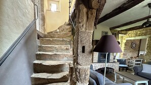 Eine Steintreppe führt zu einer zweiten Etage, eine Steinsäule, ein blaues Sofa und eine Lampe.