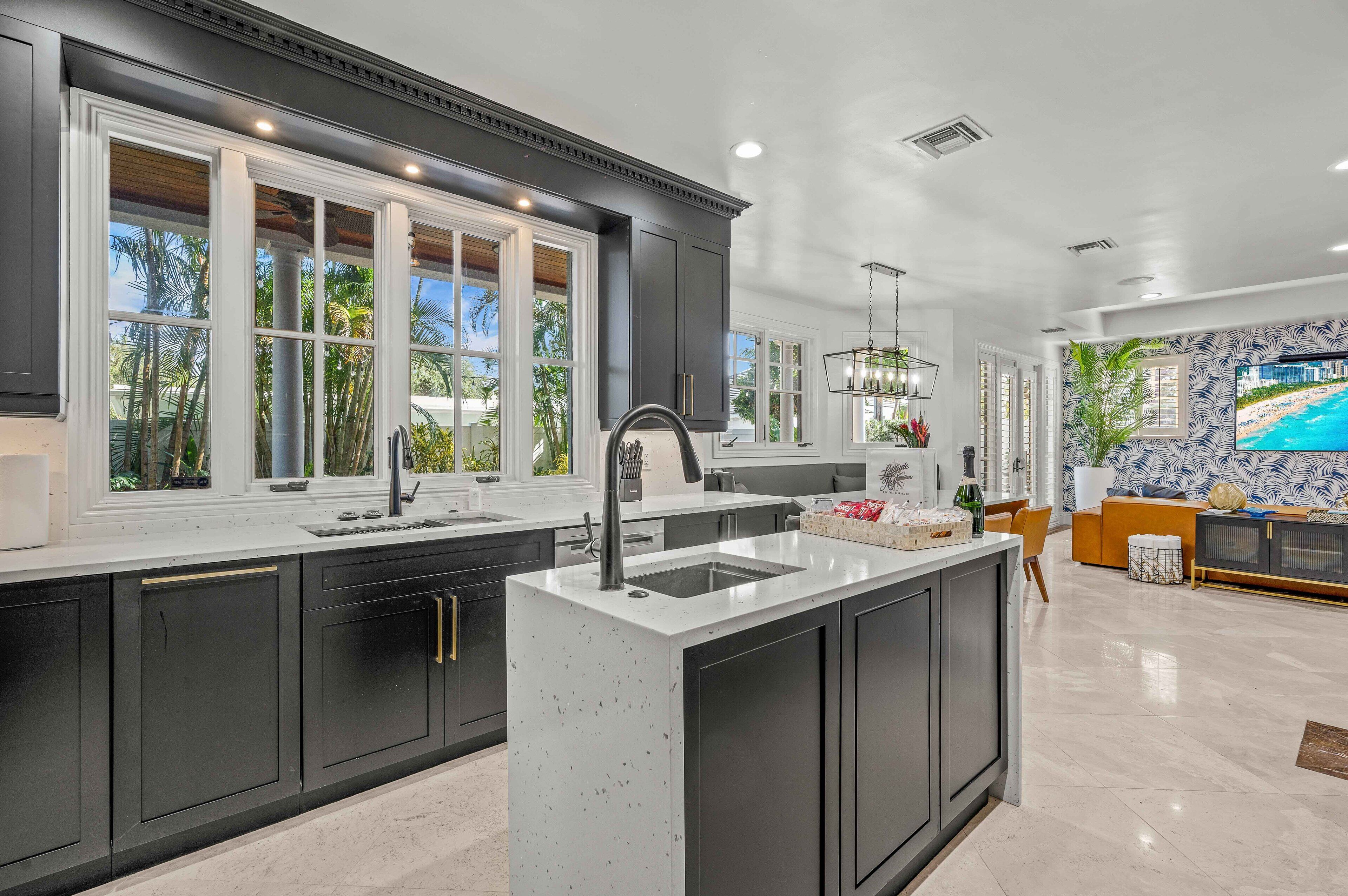 A modern kitchen with dark cabinetry, a central island, and large windows.