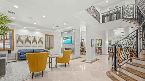 A spacious living area with a modern staircase, a sofa, and a TV. - Walk to Beach / Heated Pool / Serenity at its Finest / Hemingway Key / VlLLAS (Fort Lauderdale)