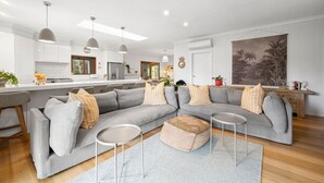 A modern living room with a grey sectional sofa, a small round table, and a patterned rug. - The Homestead on Hopkins (Aireys Inlet)